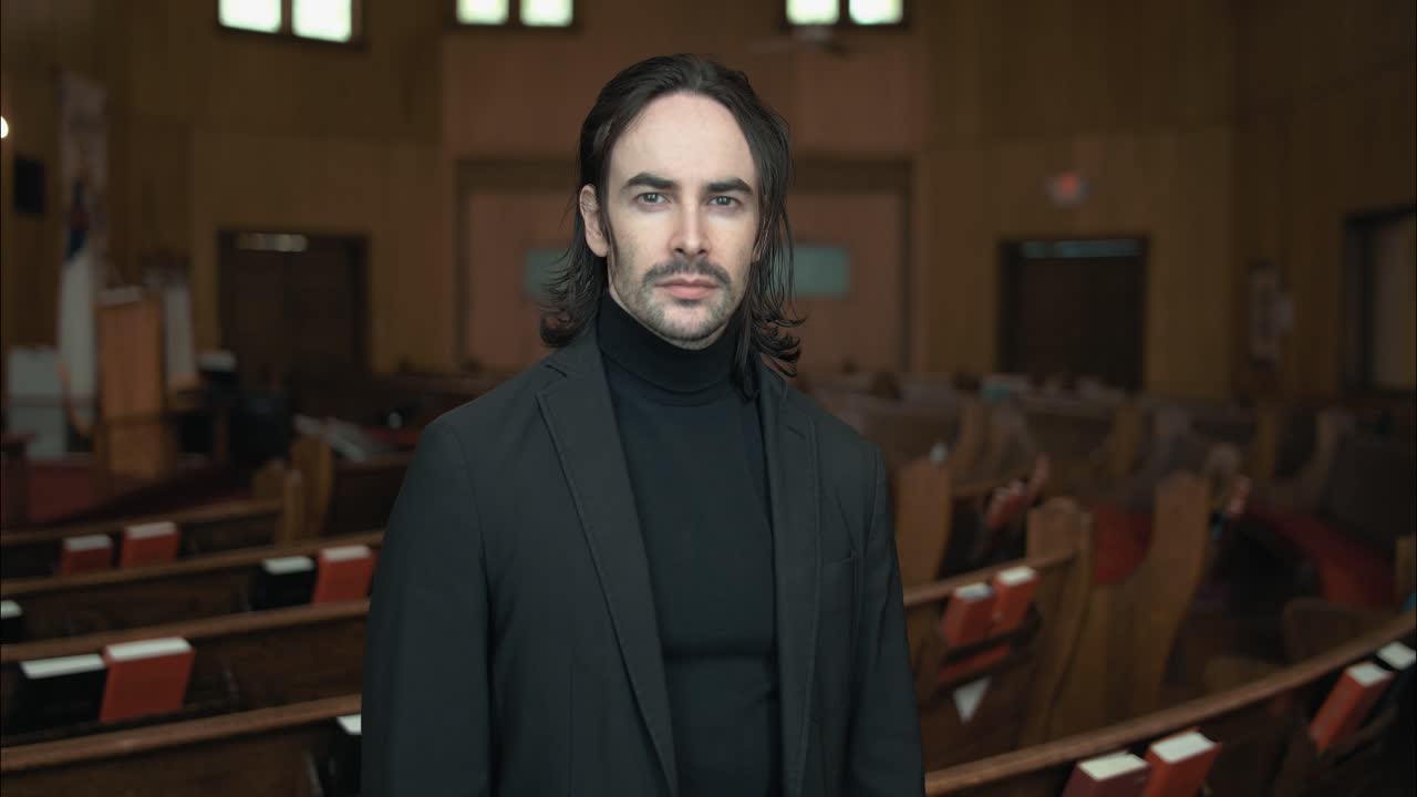 A Christian man, priest, preacher, pastor in spiritual reflection looks at camera