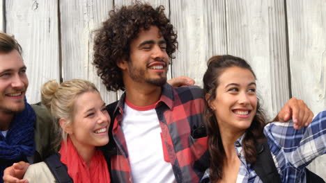 Grupo-De-Amigos-De-Pie-Con-Una-Mujer-Joven-Apuntando-Con-La-Mano-Hacia-Arriba