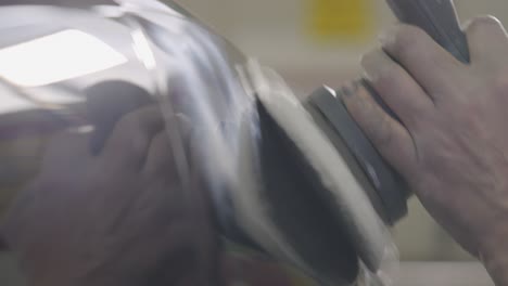 refinador de automóviles que utiliza una máquina herramienta de pulido manual en la carrocería del automóvil de cerca