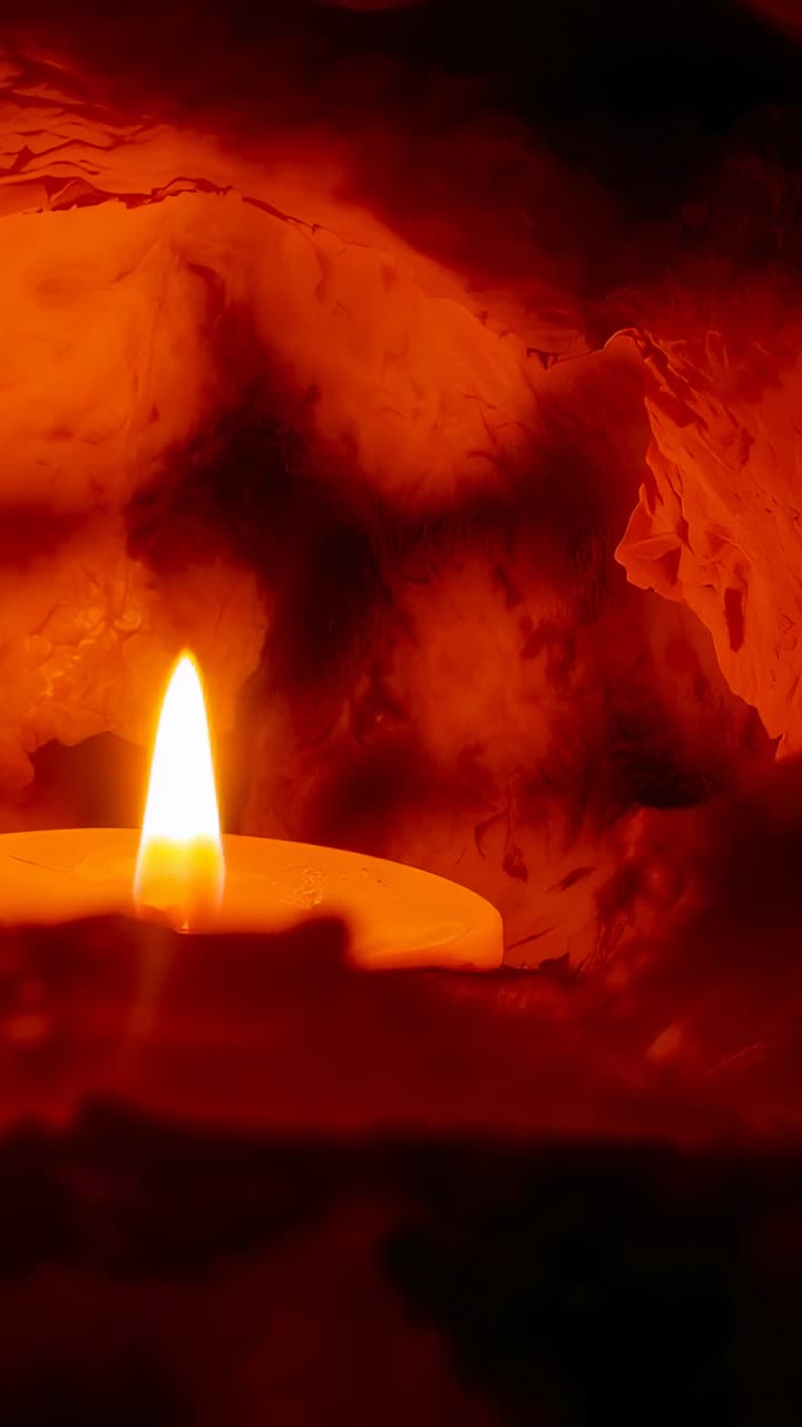 Vertical video: Flickering wax candle flame dancing in red rock alcove at footage start