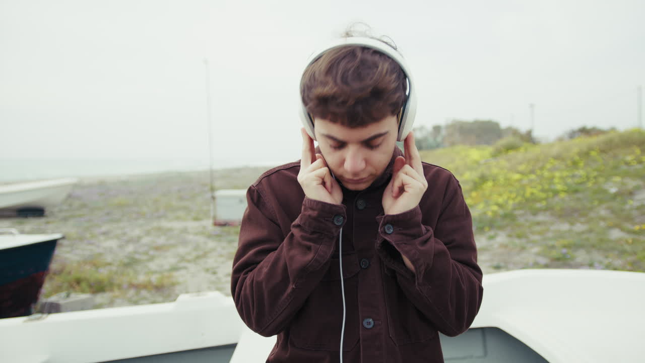 Man Relaxing On The Shore During Winter While Listening To Music