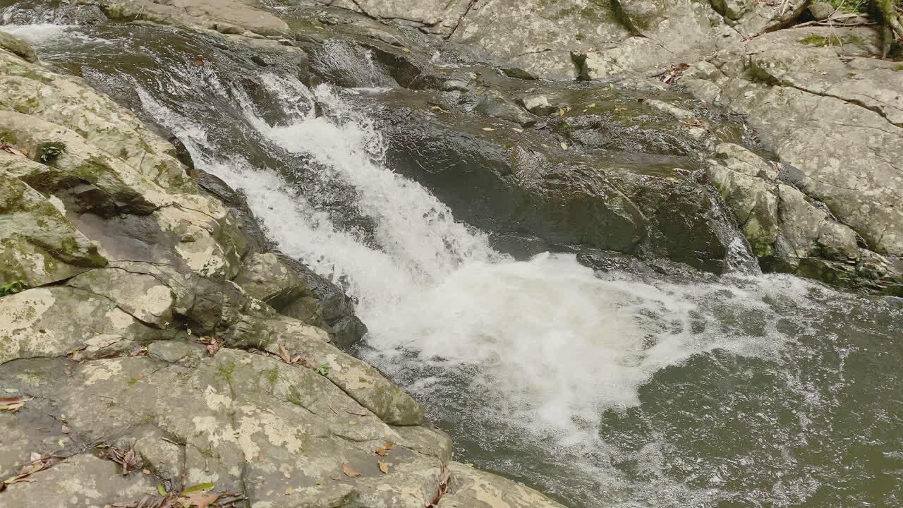 4K UHD di rapide fluviali di acqua dolce limpida e impetuosa, che scorrono a cascata su un letto di fiume di roccia preistorica.