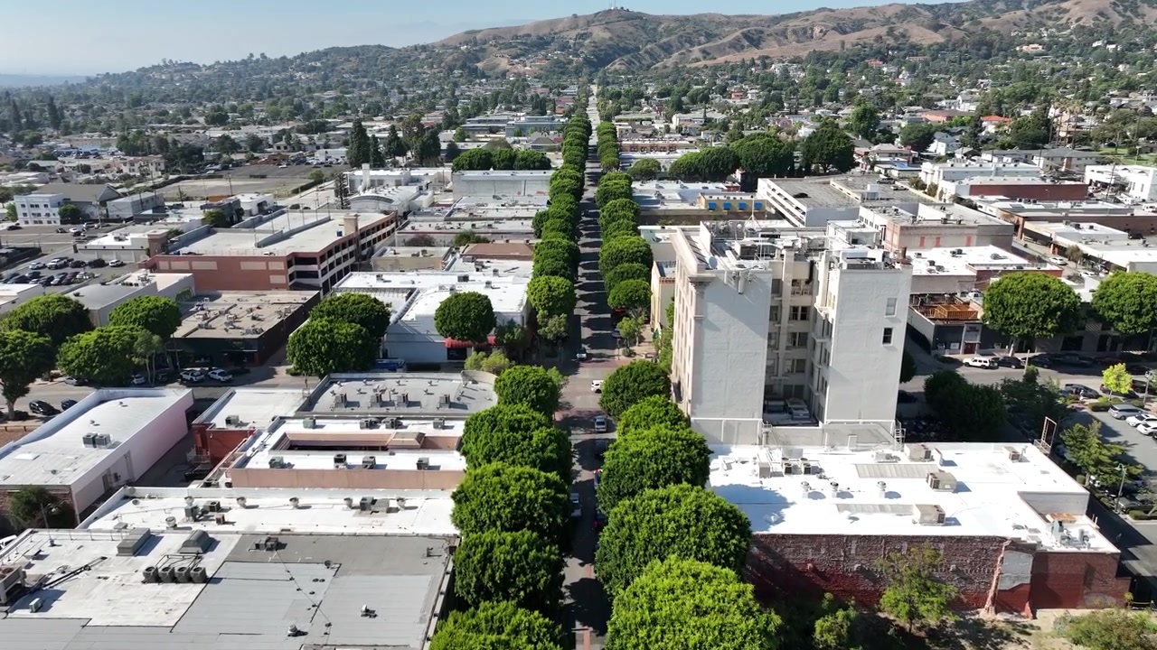 Riprese aeree ad alta risoluzione con drone del centro di Whittier, California, USA, che mostrano la Greenleaf Promenade, strade alberate, edifici commerciali, quartieri residenziali e dolci colline.
