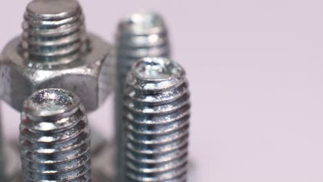 rotating group of galvanized metallic screws close-up. steinless steel bolts isolated on white background.