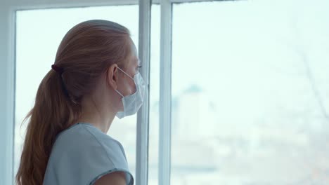 woman wearing a mask looking through a window