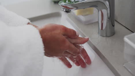 close up of biracial woman washing hands in bathroom, slow motion