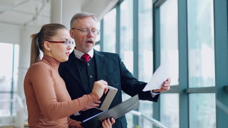 Senior businessman discussing presentation with woman assistance. Mature man and woman in an office. Video from the business office.