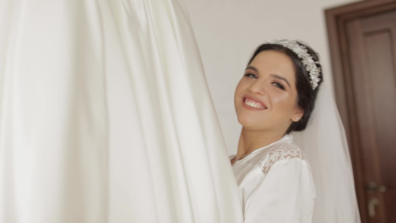 Hermosa y encantadora novia en camisón y velo corriendo hacia el vestido de novia.