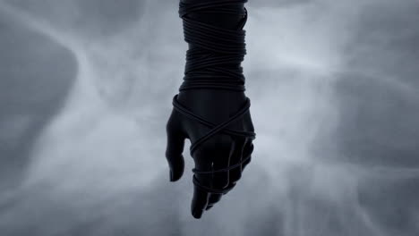 dark hand wrapped in cords on a misty background