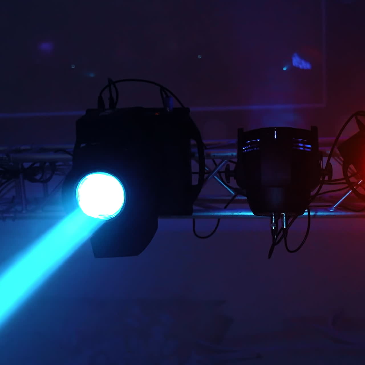 Lighting equipment flashing over the stage. Close-up spotlights with laser rays inside the disco club. Colorful lights in the modern hall glowing from the ceiling.