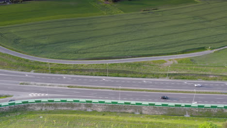 Drone-aerial-perspective-of-cars-driving-along-highway-between-farmland-fields