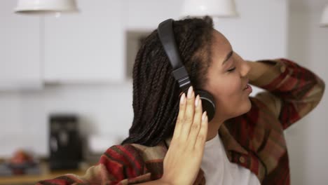 Portrait-of-the-young-African-American-woman-wearing-headphones-listening-to-the-music-at-home,-slow-motion