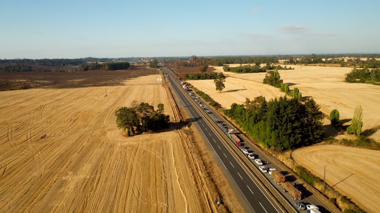 Aerial drone view of long traffic jam on rural highway due to accident, cars queued up in countryside with harvested fields, Chile