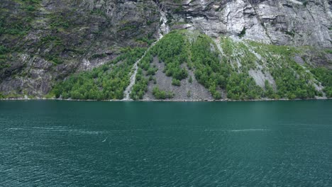massive geiranger fjord, as seen from a cruise ship, big mountains ranging out of the blue water in 4k