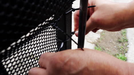 plastic net being fixed to a gate