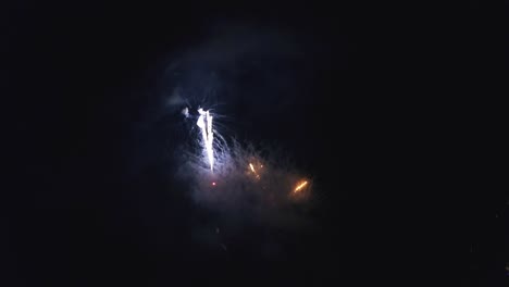 aerial flight over a fireworks display during summer time at the 4th of july, with multiple different color fireworks displays from a unique, high elevation perspective.