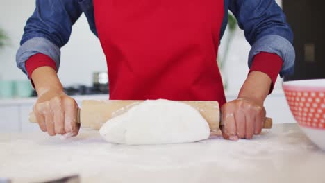 hands of african american woman rolling out dough in kitchen