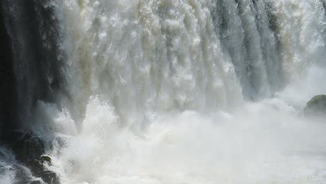 iguazu falls waterfall in argentina, slow motion view of crashing waterfall into huge plunge pool, aggressive bright clear water falling in beautiful close up detail in south america