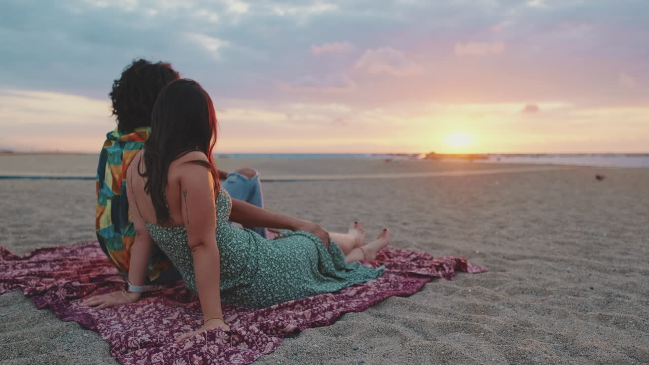 Una pareja se relaja en la playa al atardecer