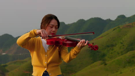 female musician in a trance-like state as she plays the violin in the mountains