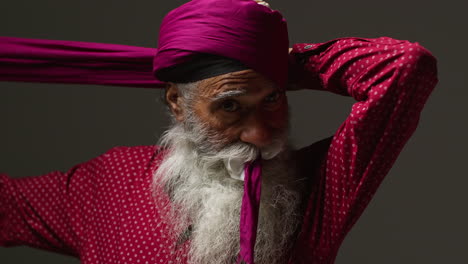 a sikh man adjusting his pink turban