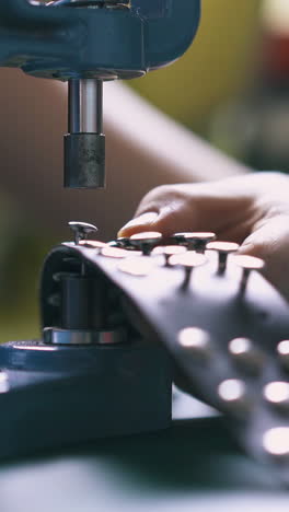 cu: professional girl designer fixes silver choker holnitens with special press machine in workshop close view