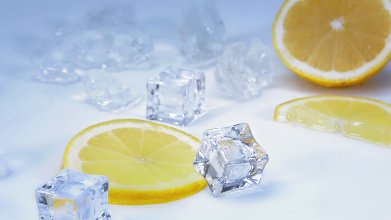 Inquadratura di gustose fette di limone su un tavolo azzurro e bianco con rinfrescanti cubetti di ghiaccio