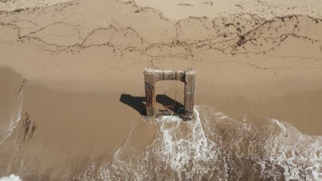 aerial view of old broken pier made of cement in the middle of the ocean near santa cruz california