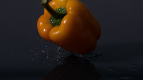 Gelbe-Paprika-Fallen-Vor-Schwarzem-Hintergrund