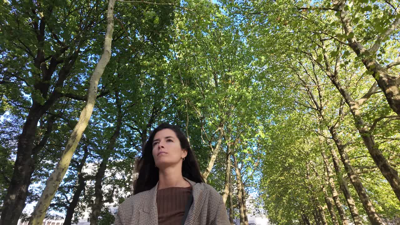 Woman walking under trees in a park