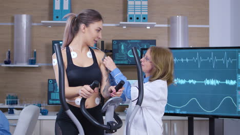 female scientist attaching electrodes on woman athlete body