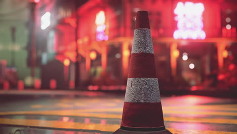 red traffic cone on a city street at night