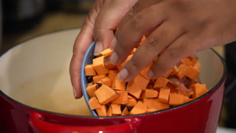 Dumping-chopped,-diced-sweet-potato-cubes-into-a-pot-to-boil---slow-motion