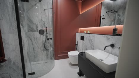 stylish bathroom featuring marble walls, a round mirror, terracotta tones, and matte black fixtures for a chic and contemporary feel