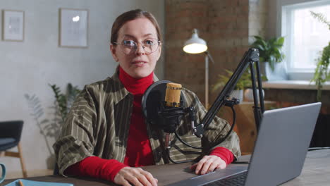 cheerful female vlogger speaking at camera in recording studio