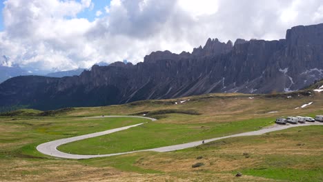 lejos un ciclista irreconocible en bicicleta cuesta arriba paso giau, montaña rocosa
