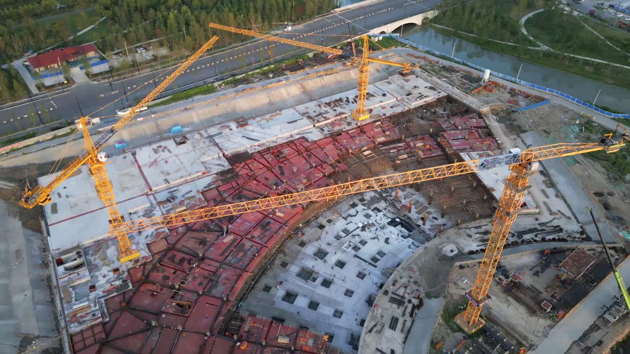 drone vuela sobre el sitio de construcción con tres grúas amarillas construyendo un distrito residencial en el desarrollo urbano moderno inteligente