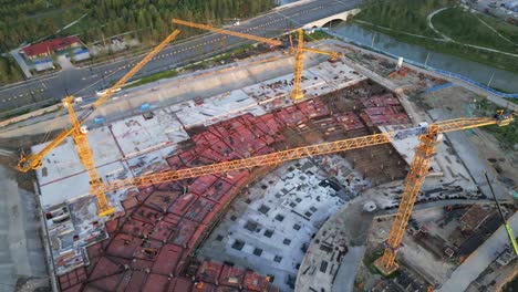 drone fly above construction site with three yellow crane building a residential district in smart modern urban city development