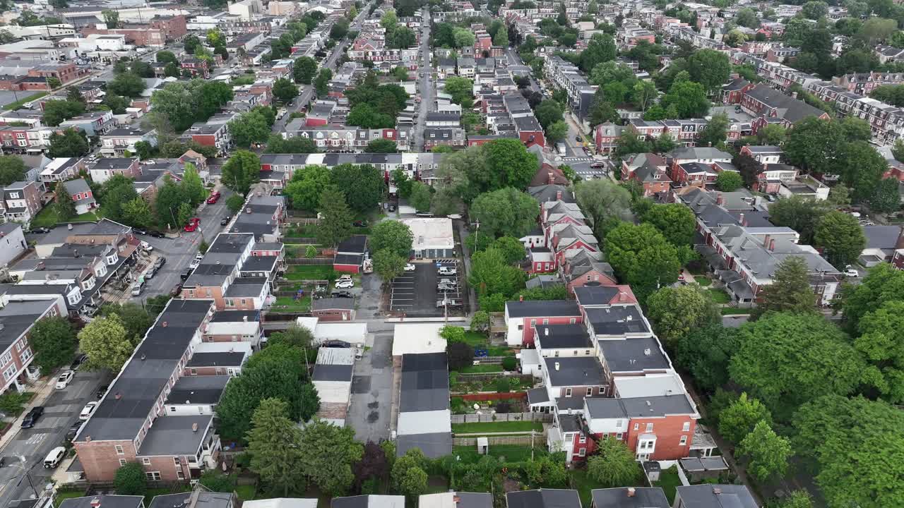 Lancaster City with row of house and townhouses in american city. Aerial lateral wide shot. Colored roofs with green trees. Straight streets in historic suburb of town.