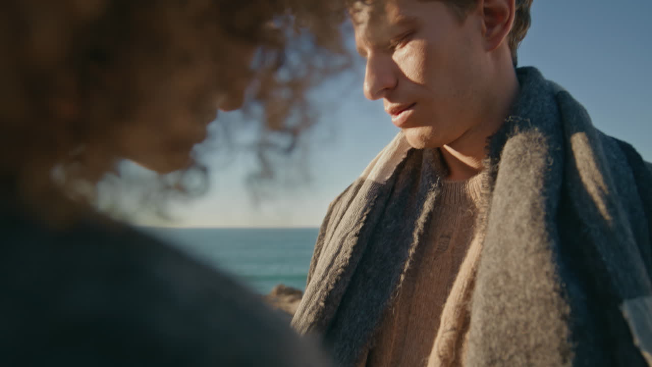 Melancholy newlyweds dating ocean closeup. Diverse man woman touching hands