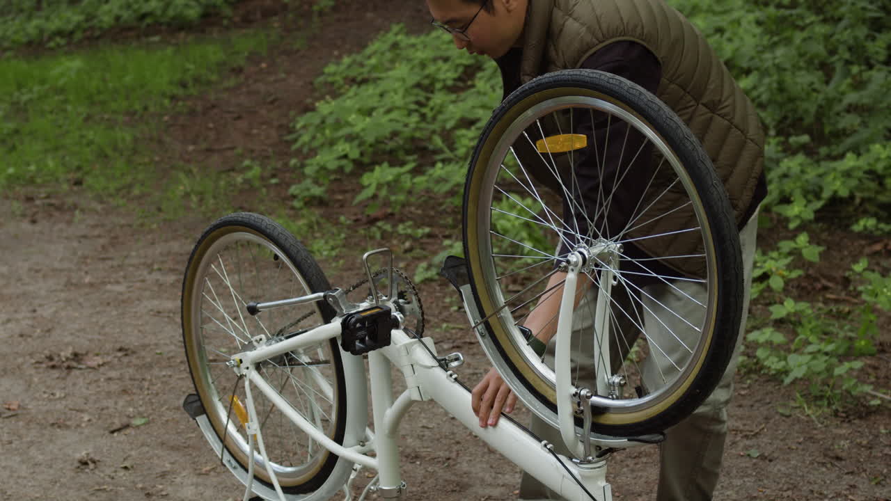 Man repairing a bicycle in a park