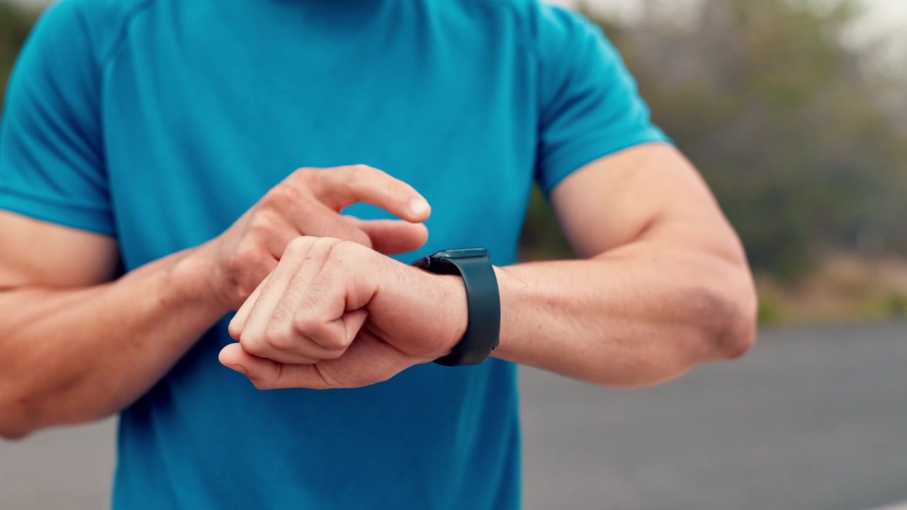 Uomo atletico che controlla lo smartwatch prima di iniziare la corsa