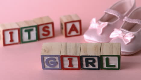 its a girl message in letter blocks beside pink booties