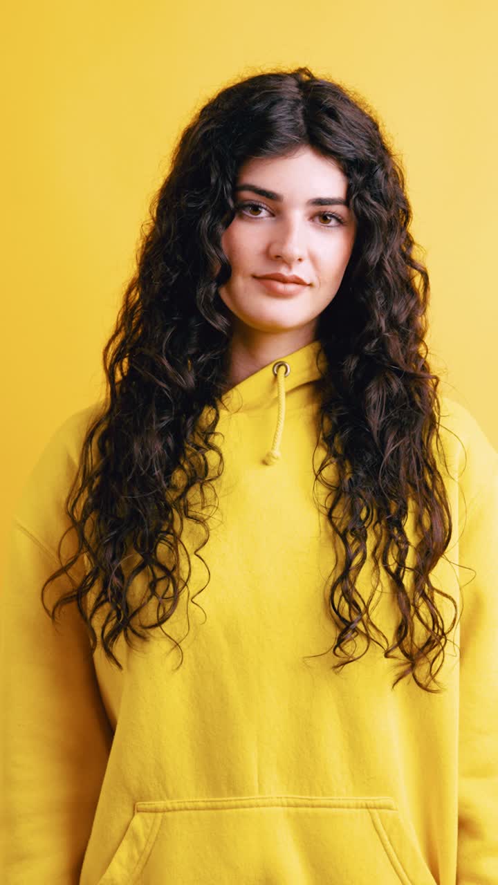 Portrait of a woman with curly hair wearing a yellow hoodie