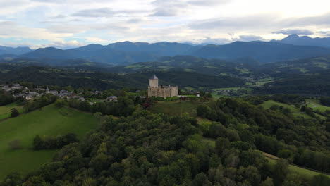 Toma-Aérea-Del-Castillo-De-Mauvezin-En-Lo-Alto-De-Una-Colina-Verde.