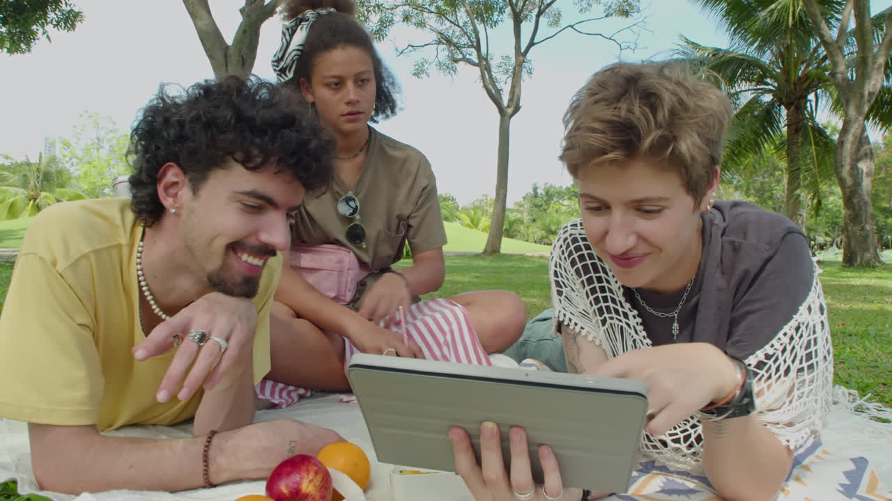 Gen Z Friends Chatting and Using Tablet on Picnic in Park