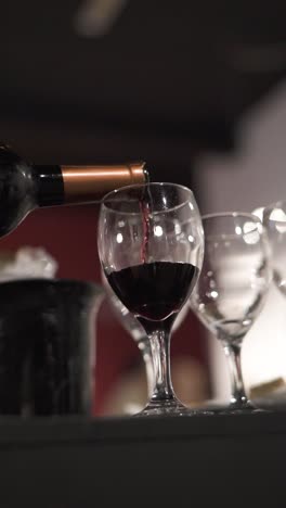 Slow-motion-closeup-of-bottle-pouring-red-wine-into-crystal-glass-at-business-dinner-reception