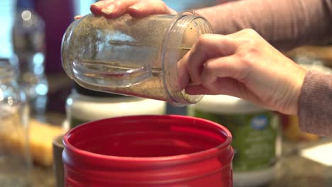 Blended-marijuana-buds-put-in-container-for-salve-creation,-close-up