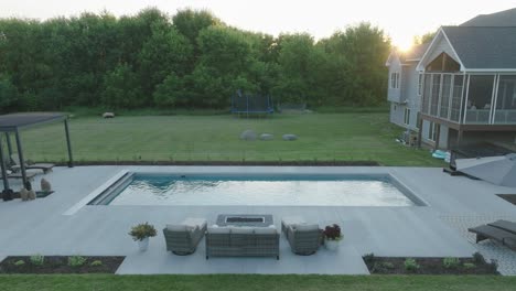 balanced view of backyard pool and patio area with golden sunset and modern design