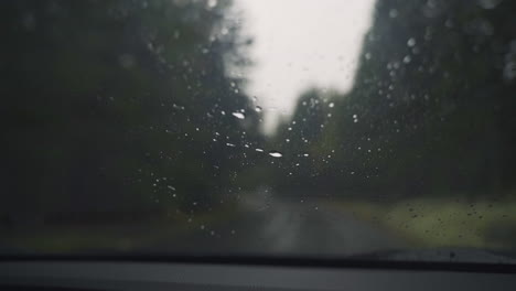 closeup wet rain hitting windshield and being cleaned by window wipers in slow motion